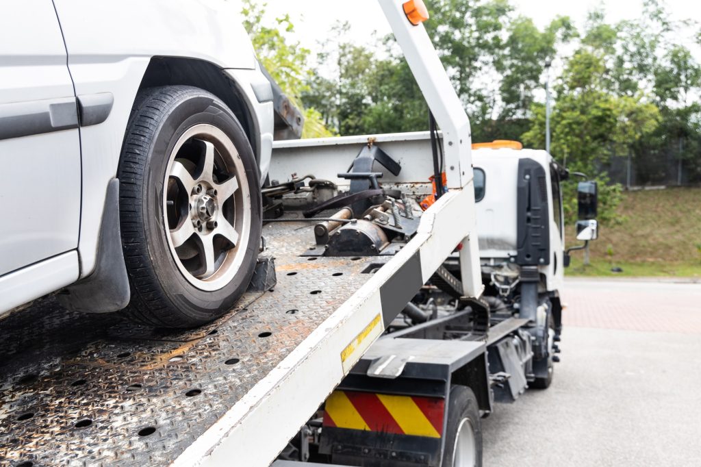 Cable attached to broken down car being pulled onto tow truck