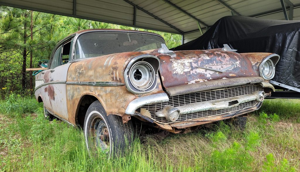 Old rusted car in junk yard hoping to salvage some parts.